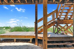 Eine Holzterrasse mit Blick auf Strand und Dünen.