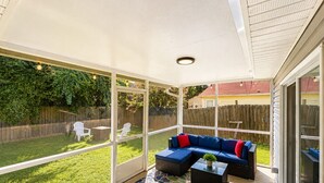 A covered patio with a sectional sofa, a coffee table, and a chair. - Captain`s Quarters - New Listing (Pensacola)