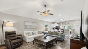 A living room with a sofa, armchair, coffee table, and a ceiling fan. - Captain`s Quarters - New Listing (Pensacola)