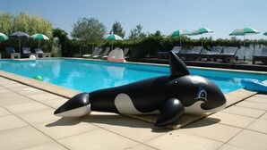 Una piscina con sillones de descanso y sombrillas.