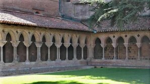 Un patio con varios arcos y un edificio de ladrillo al fondo.