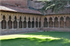 A courtyard with a series of arches and a brick building in the background. - Roussel (Saint-Paul-d'Espis)