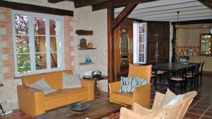Una sala de estar acogedora con un sofá, sillones, una mesa de centro y un comedor con mesa y sillas.
