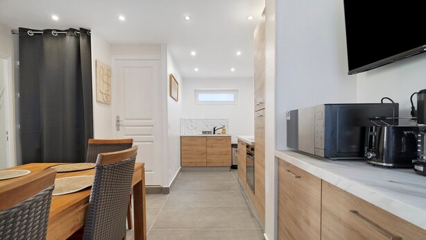 Una cucina moderna con zona pranzo, mobili in legno, TV a schermo piatto e macchina del caffè.
