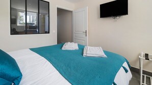 Una camera d'albergo con un letto, una TV fissata al muro e una finestra con vista.