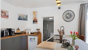 Een moderne keuken met een ingebouwde magnetron, koffiezetapparaat en een houten snijplank.