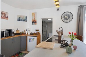 A modern kitchen with a built-in microwave, coffee maker, and a wooden cutting board. - Stay at "L'Ensoleillé" – City Center / Train Station (Les Sables-d'Olonne)