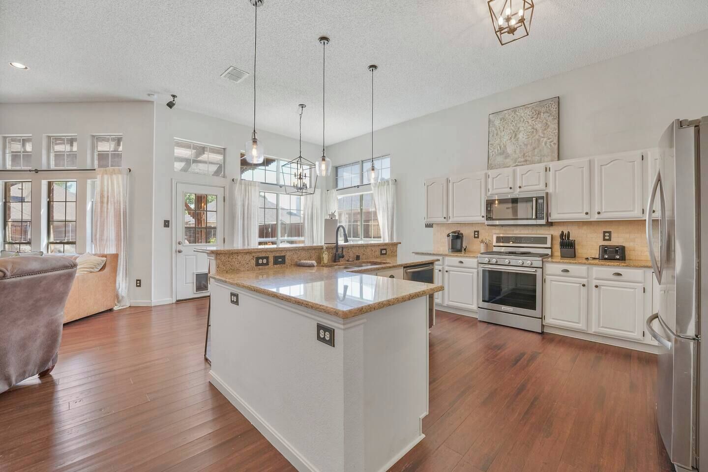 A spacious kitchen with white cabinetry, a central island, and a dining area with a sofa.
