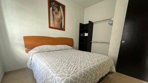 Een slaapkamer met een bed, een kast, een deur en een schilderij aan de muur.