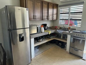 A compact kitchen with a stainless steel refrigerator, a stove, and a microwave. - SMALL HOUSE IN NUEVO VALLARTA WITH THREE BEDROOMS AND TWO BATHROOMS IN A QUIET NEIGHBORHOOD (Mezcales)