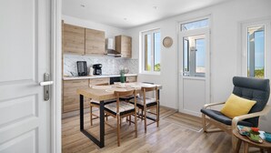 Eine moderne Küche mit Holdekor-Schränken, einer Marmorarbeitsplatte und einem Essbereich mit Holztisch und Stühlen.