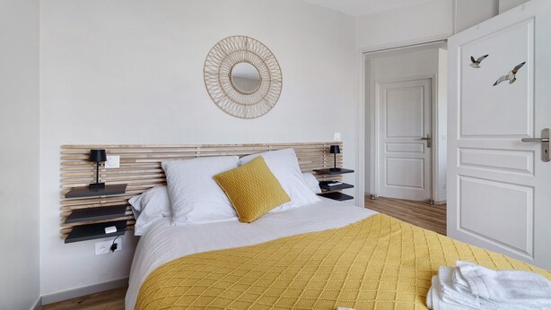 A bedroom with a bed, bedside tables, a mirror, and a door.