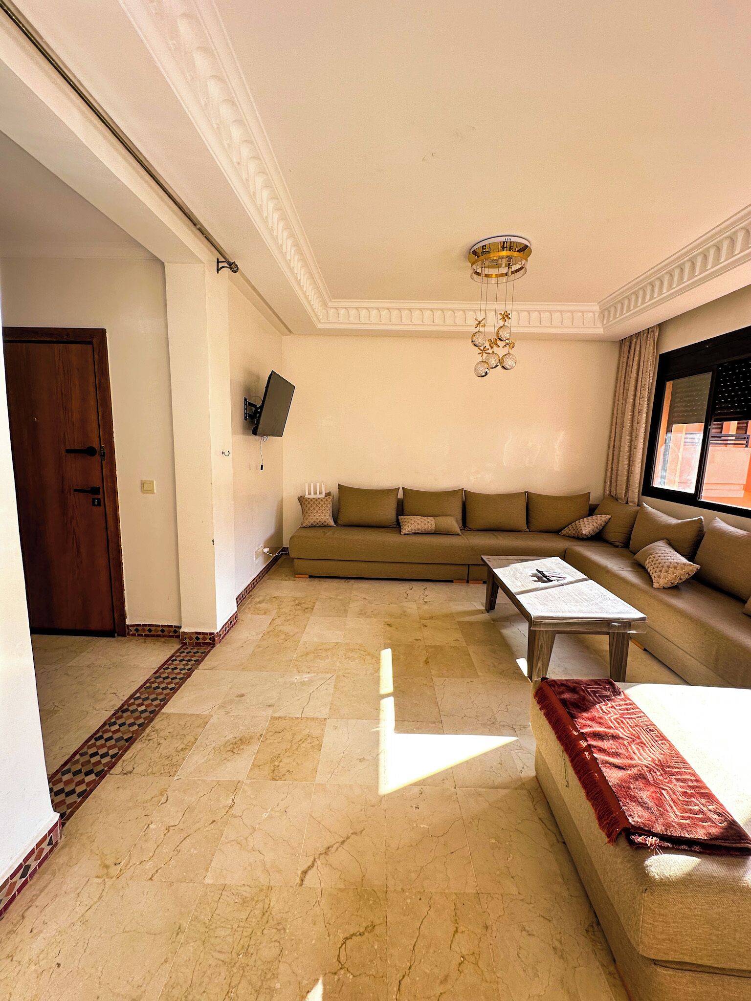 A living room with a sofa, a coffee table, and a television mounted on the wall.