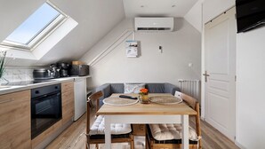 Een compacte keuken met dakraam, een eethoek met tafel en stoelen, en een ingebouwde airconditioning.