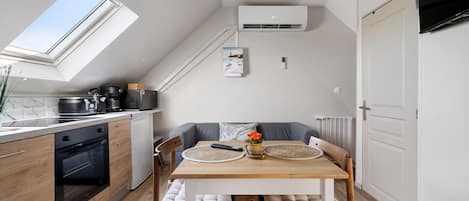 A compact kitchen with a skylight, a dining area with a table and chairs, and a built-in air conditioning unit.