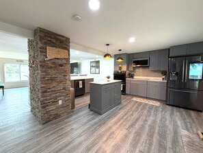A modern kitchen with grey cabinets, a central island, and pendant lighting. - Lakefront Retreat-Private Dock, Kayaks & Fire Pit -Perfect for Families & Groups (Plymouth)