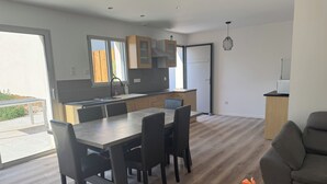 A modern kitchen with a dining area, wooden cabinets, and a grey sofa. - House with a garden in Saintes (La Clisse)