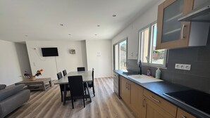 A modern kitchen with a dining area, wooden flooring, and large windows. - House with a garden in Saintes (La Clisse)