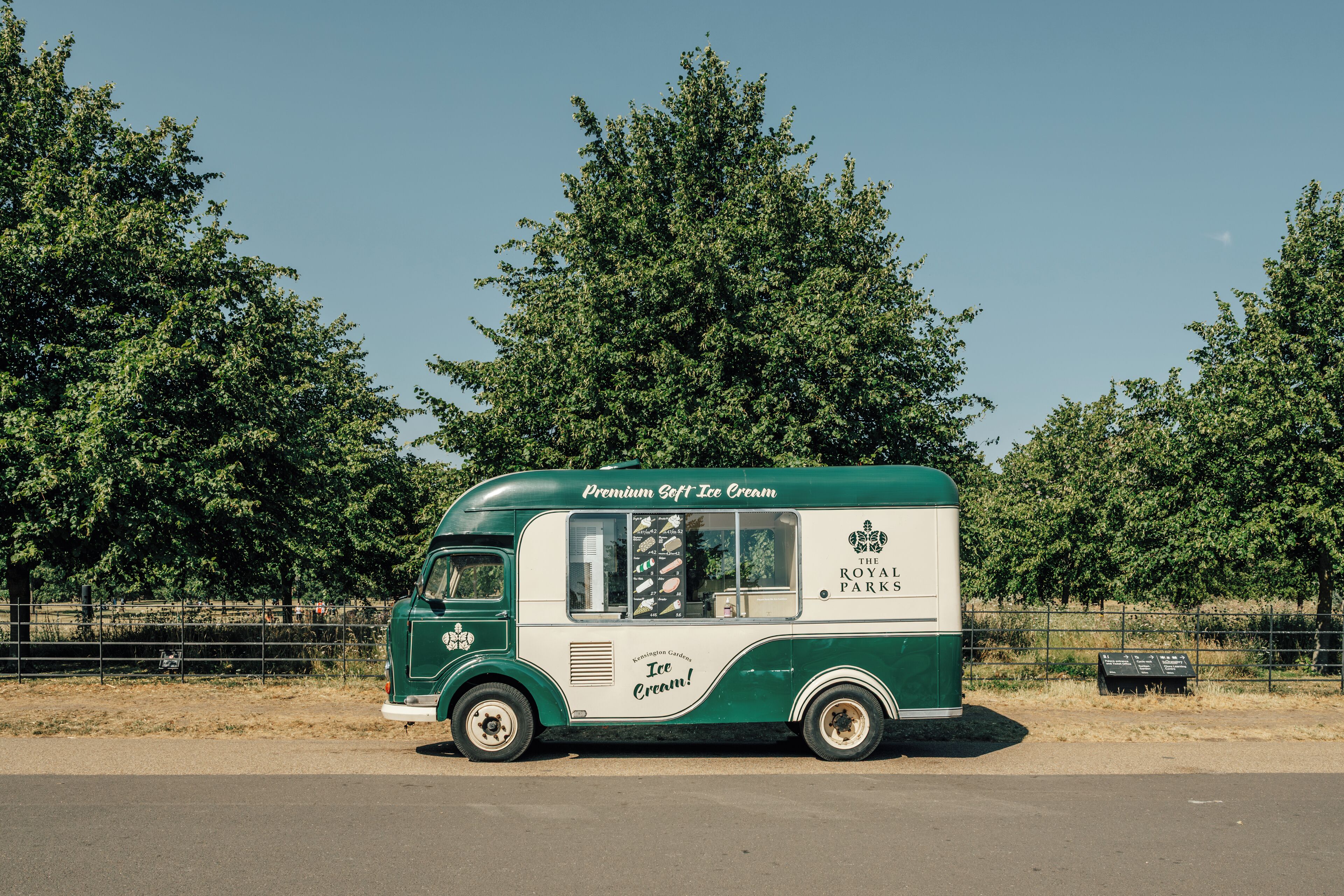 A vintage ice cream truck parked on a road with trees in the background.
