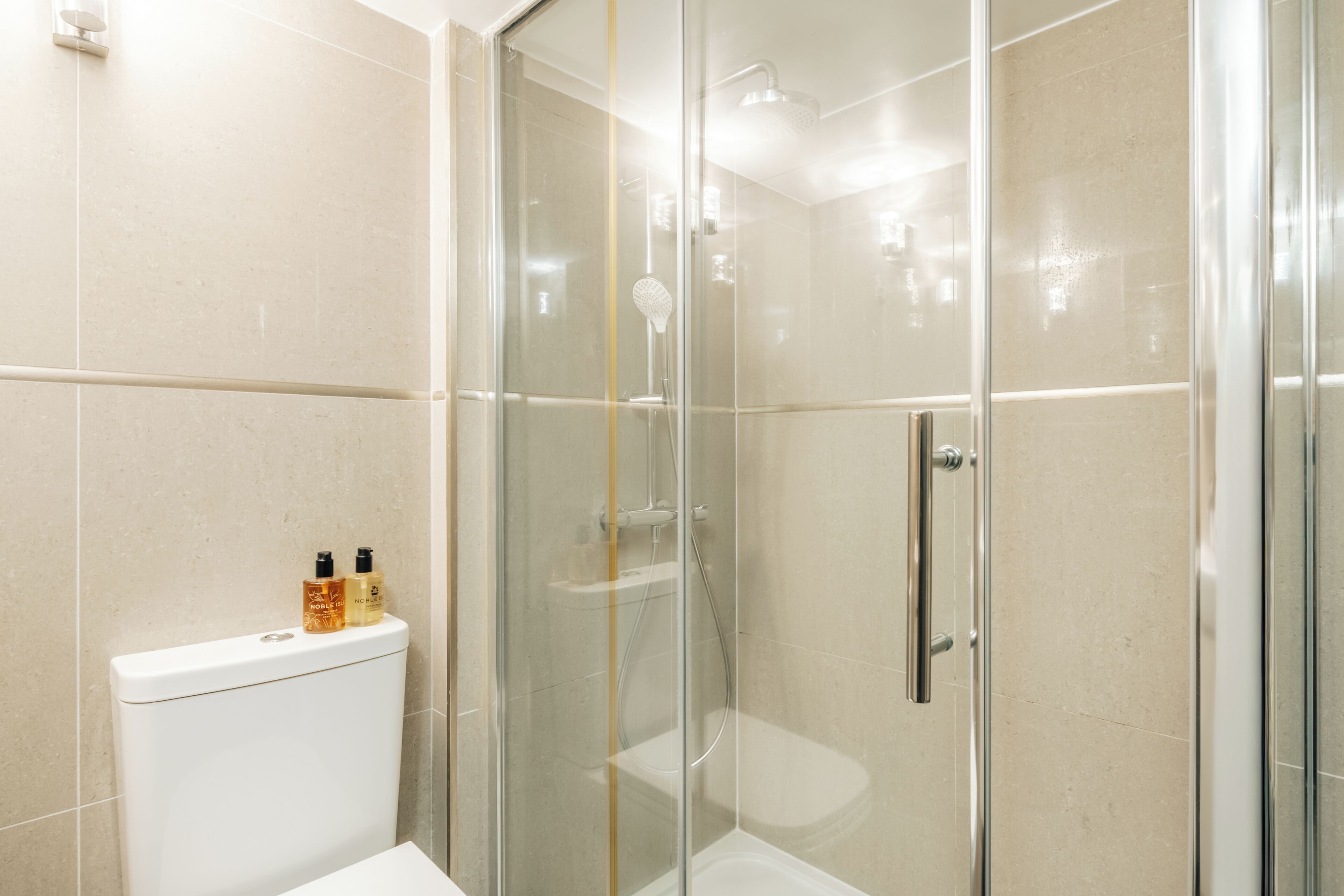 Ein Duschbereich mit Glasabtrennung, Toilette und Waschbecken.