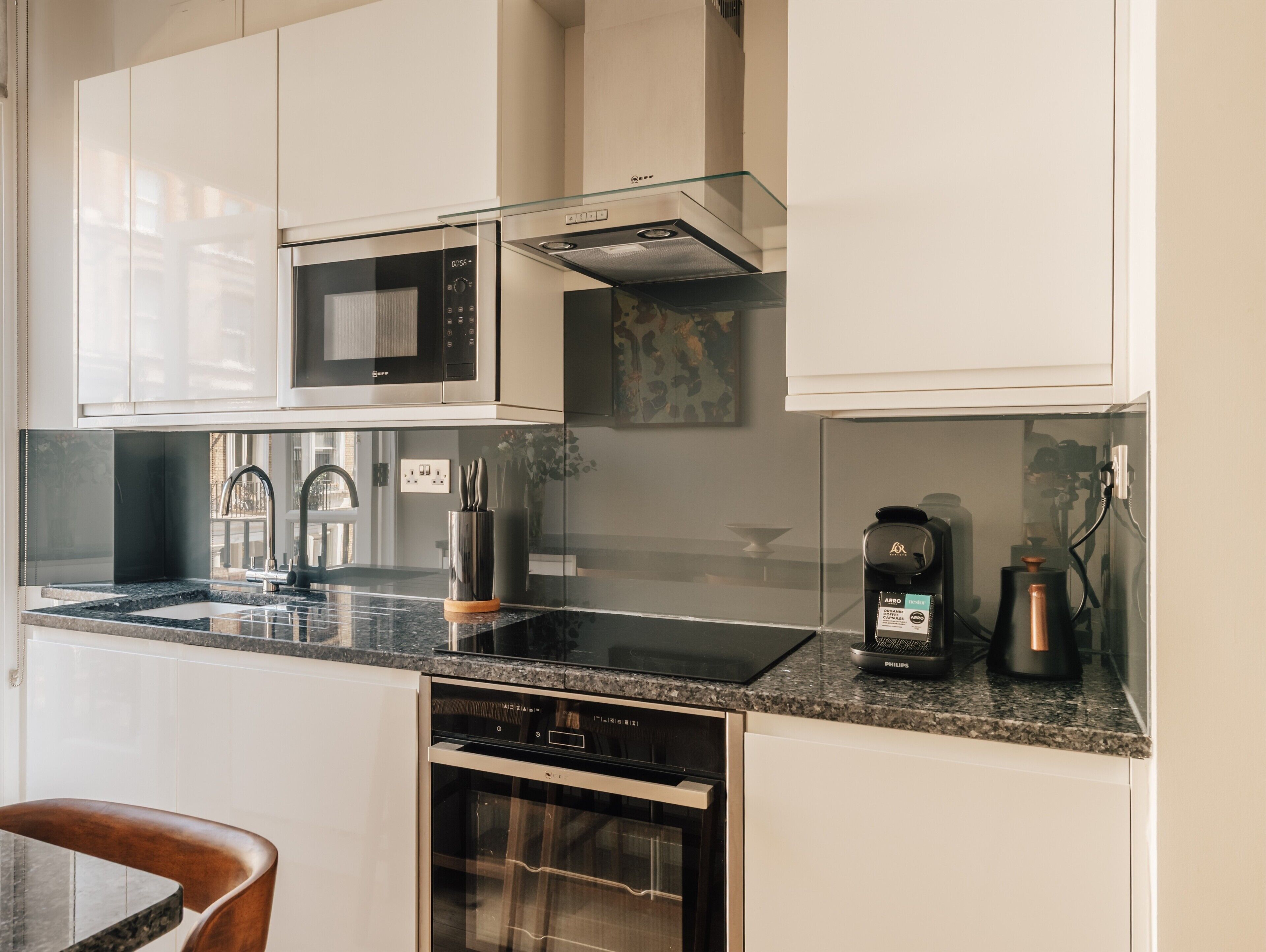 A modern kitchen with a built-in microwave, stainless steel appliances, and a coffee maker.