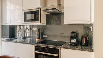 A modern kitchen with a built-in microwave, stainless steel appliances, and a coffee maker.