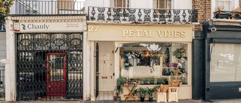 A flower boutique with a closed sign, a red door, and various plants displayed outside.