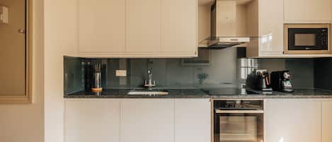 A modern kitchen with white cabinetry, a stainless steel range hood, a built-in microwave, and a dishwasher.