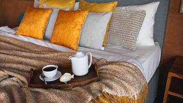Una cama bien hecha con una bandeja de té y una tetera, junto con un salero con forma de pez.