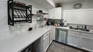 A modern kitchen with white cabinets, a dishwasher, a coffee maker, and a wine rack.