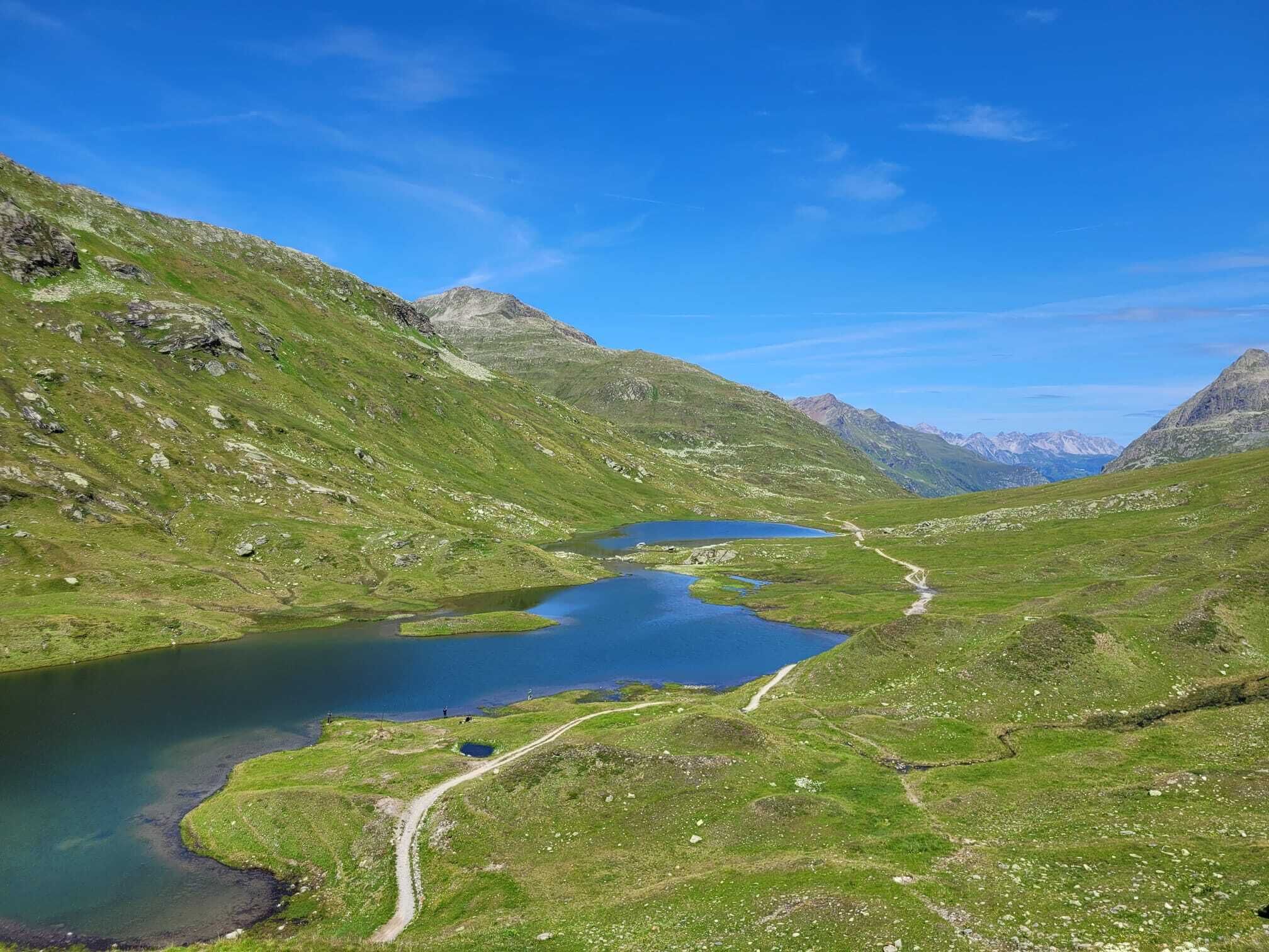 Un paisaje montañoso con un lago y un sendero sinuoso.