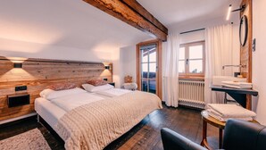 A bedroom with a wooden headboard, a bed with white bedding, a small table with towels, and a window with curtains. - Haus Richard Falch – Chalet in St. Anton, 2 Min. to Galzigbahn (Sankt Anton am Arlberg)