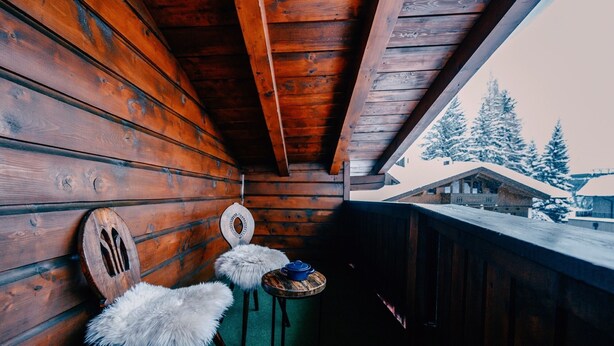 A wooden cabin with a balcony, two chairs, and a table. - Haus Richard Falch – Chalet in St. Anton, 2 Min. to Galzigbahn (Sankt Anton am Arlberg)