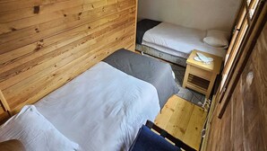 A compact room with wooden walls and a sloped ceiling, featuring two beds and a small table. - hevas suite (çalmlıhemşin)