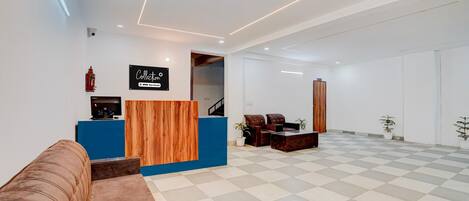 A reception area with a blue counter, a wooden accent wall, a brown sofa, and a checkered floor.