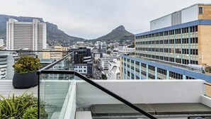 Eine Stadtsicht mit einem markanten Berg im Hintergrund, modernen Gebäuden und einer Glasreling.