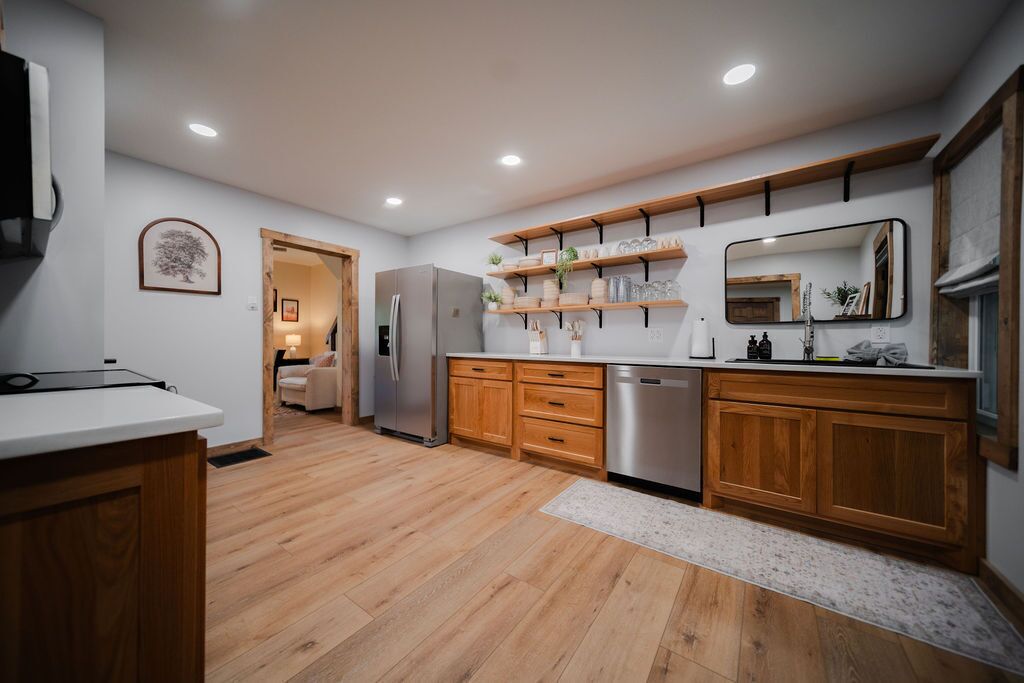 A modern kitchen with wooden cabinets, a stainless steel refrigerator, and a built-in dishwasher.