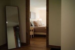 A bedroom with a bed, bedside table, and a wall-mounted lamp. - Frog's Landing | Hocking Hills, Hot Tub, Firepit (McArthur)