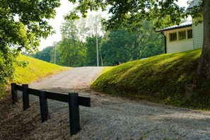 A gravel road leading to a house with a wooden fence on the left.