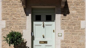 A light green door with a small window above it, a potted plant to the left, and a house number plaque to the right. - Gorgeous Georgian Townhouse in Central Frome (Somerset)