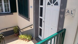 A building entrance with a white door, a balcony with a green railing, and a sign indicating a local lodging.