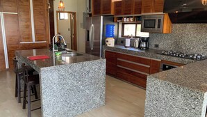 A modern kitchen with granite countertops, stainless steel appliances, and wooden cabinetry.