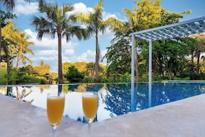 A poolside view with a pergola and palm trees. - Luxury Pool Condo Near Beach & Downtown (Punta Cana)