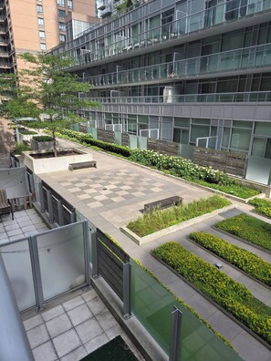 A modern building with multiple floors, a rooftop garden with various plants, and a checkered pavement area. - Cozy 1-bedroom apartment with AC steps to attractions in downtown Toronto (Toronto)