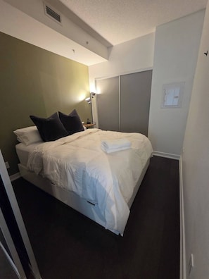 A neatly made bed with pillows, a bedside lamp, and a folded towel. - Cozy 1-bedroom apartment with AC steps to attractions in downtown Toronto (Toronto)