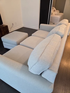 A room with a sofa bed, a small table, and a wall-mounted TV. - Cozy 1-bedroom apartment with AC steps to attractions in downtown Toronto (Toronto)