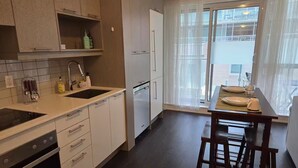 Ett modernt kök med en inbyggd ugn, en diskho och en matplats med ett bord dukat för två personer.