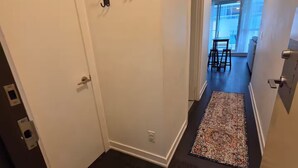 A hallway with a dark wooden floor, a patterned rug, and a door with a white frame.