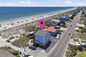 Une zone résidentielle côtière avec des propriétés donnant sur la plage, une route et des parasols de plage.