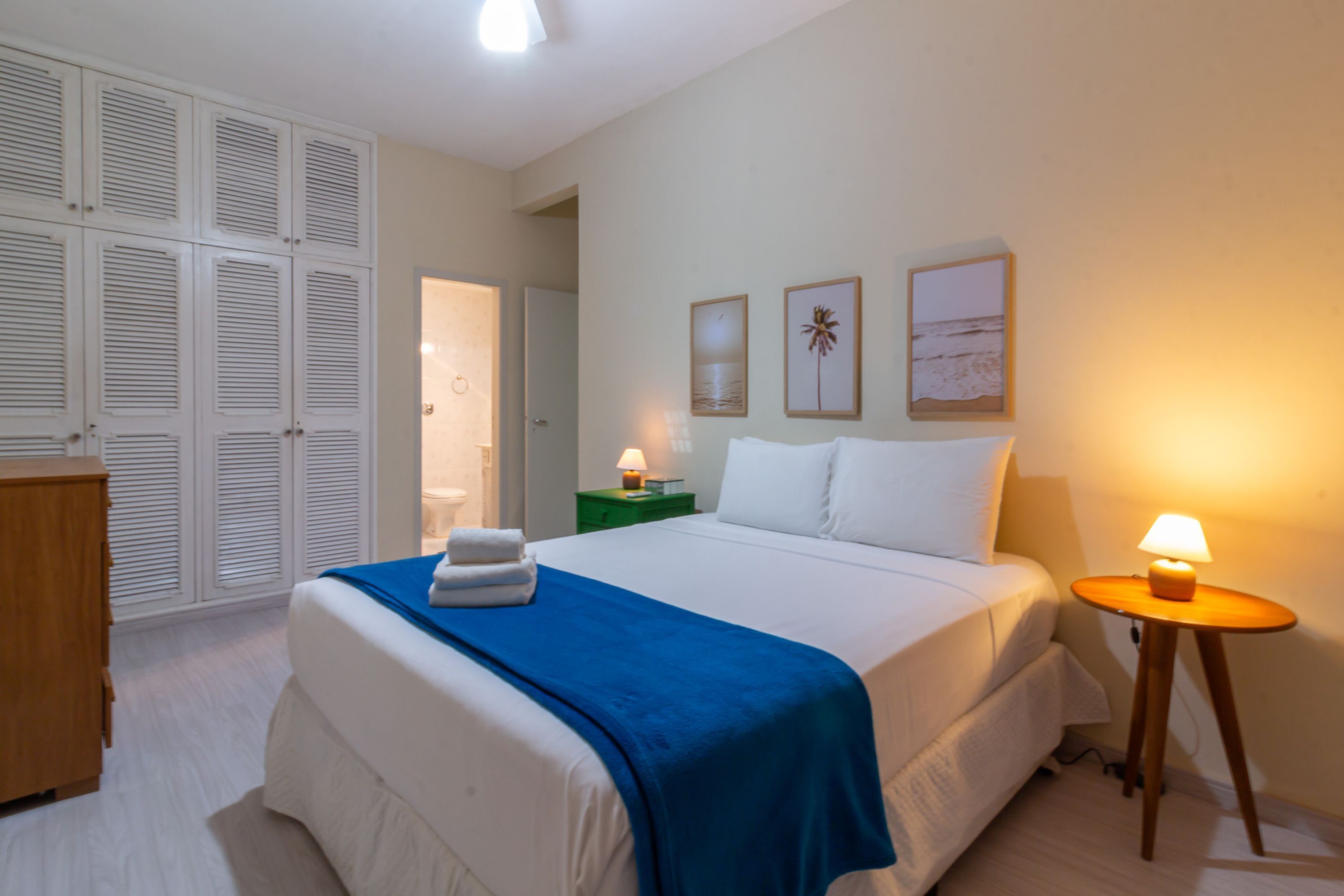 Een slaapkamer met een bed, nachtkastjes, een kledingkast en een deur naar een andere kamer.